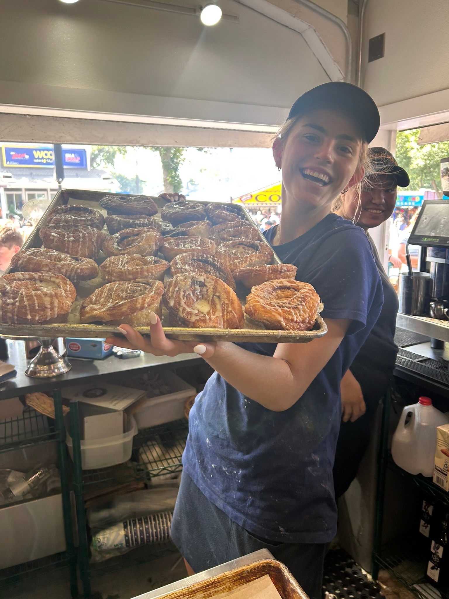 French Meadow staff member smiling and holding a fresh tray of pastries at the Fair