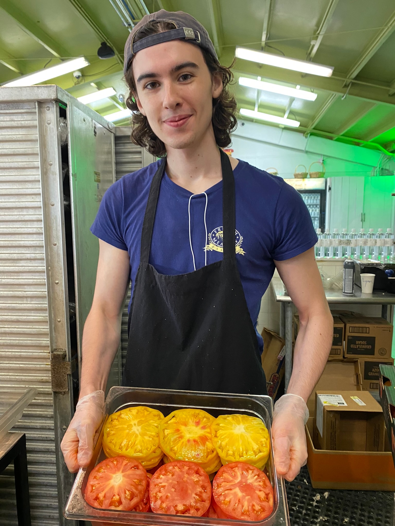 French Meadow team member holding a tray of fresh heirloom tomatoes in the kitchen
