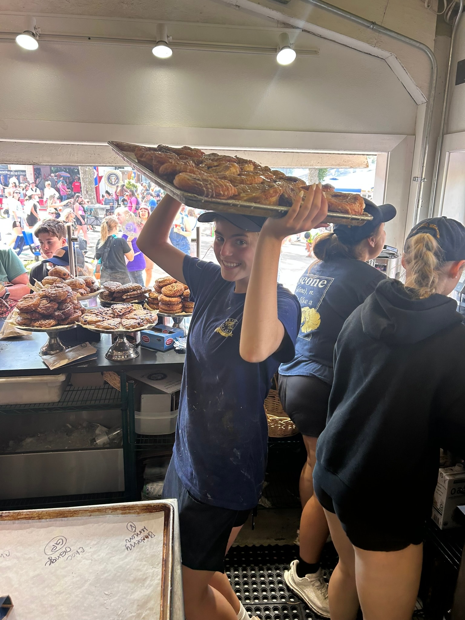 French Meadow team member balancing a tray of baked goods overhead in the busy kitchen