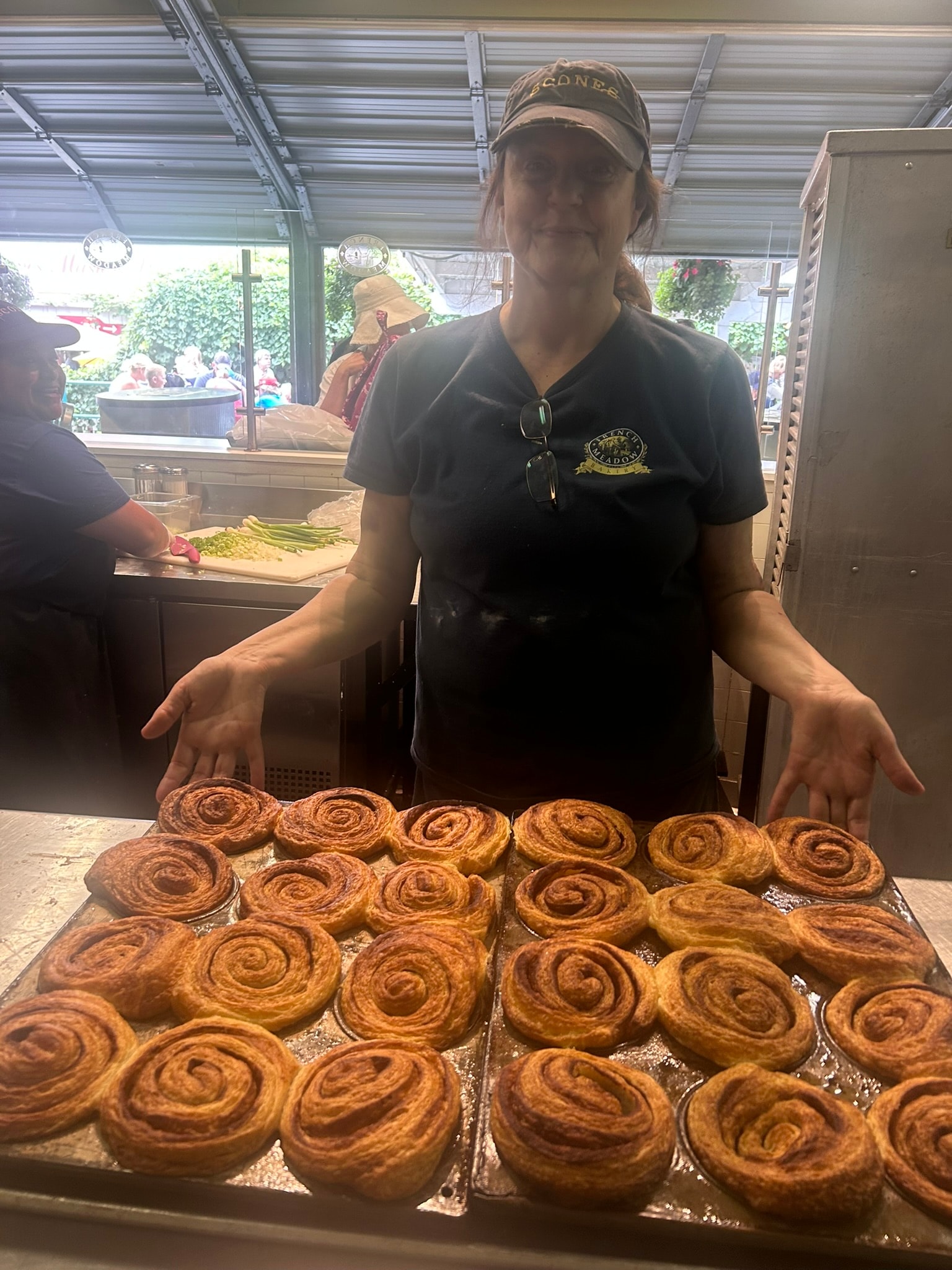 French Meadow staff member presenting a full tray of cinnamon rolls at the Fair